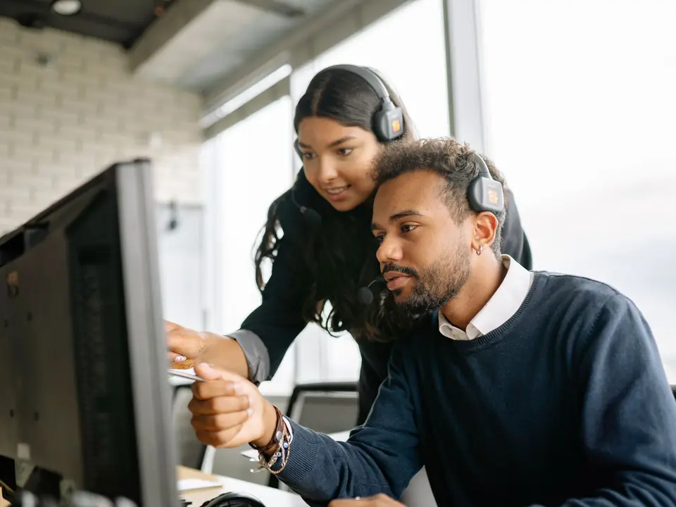 An IT support specialist helping a colleague at a computer